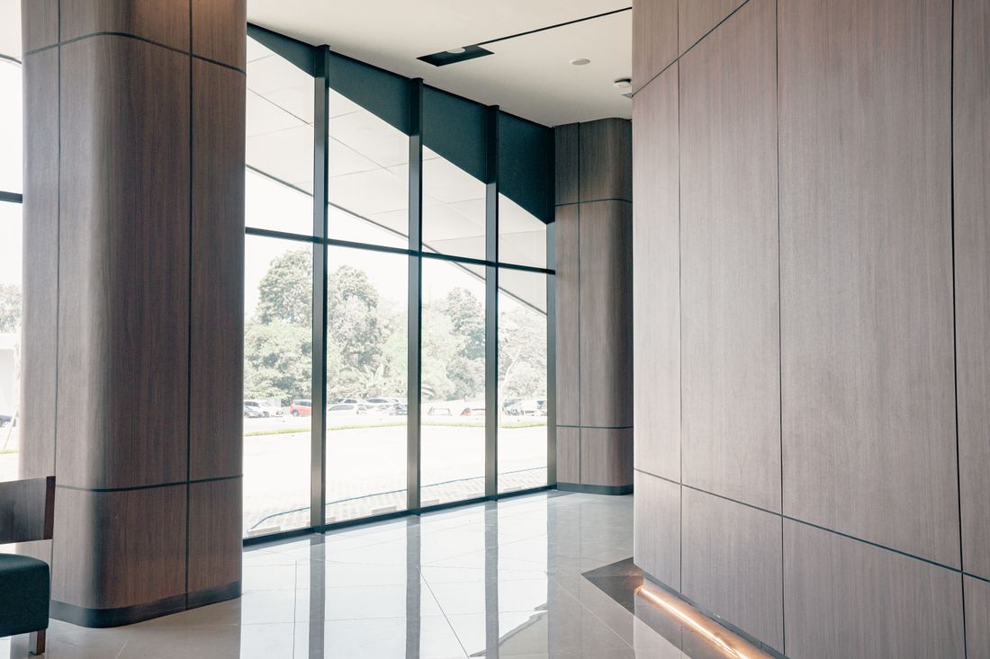 A quiet modern office lobby with wood-paneled walls and floor-to-ceiling windows.