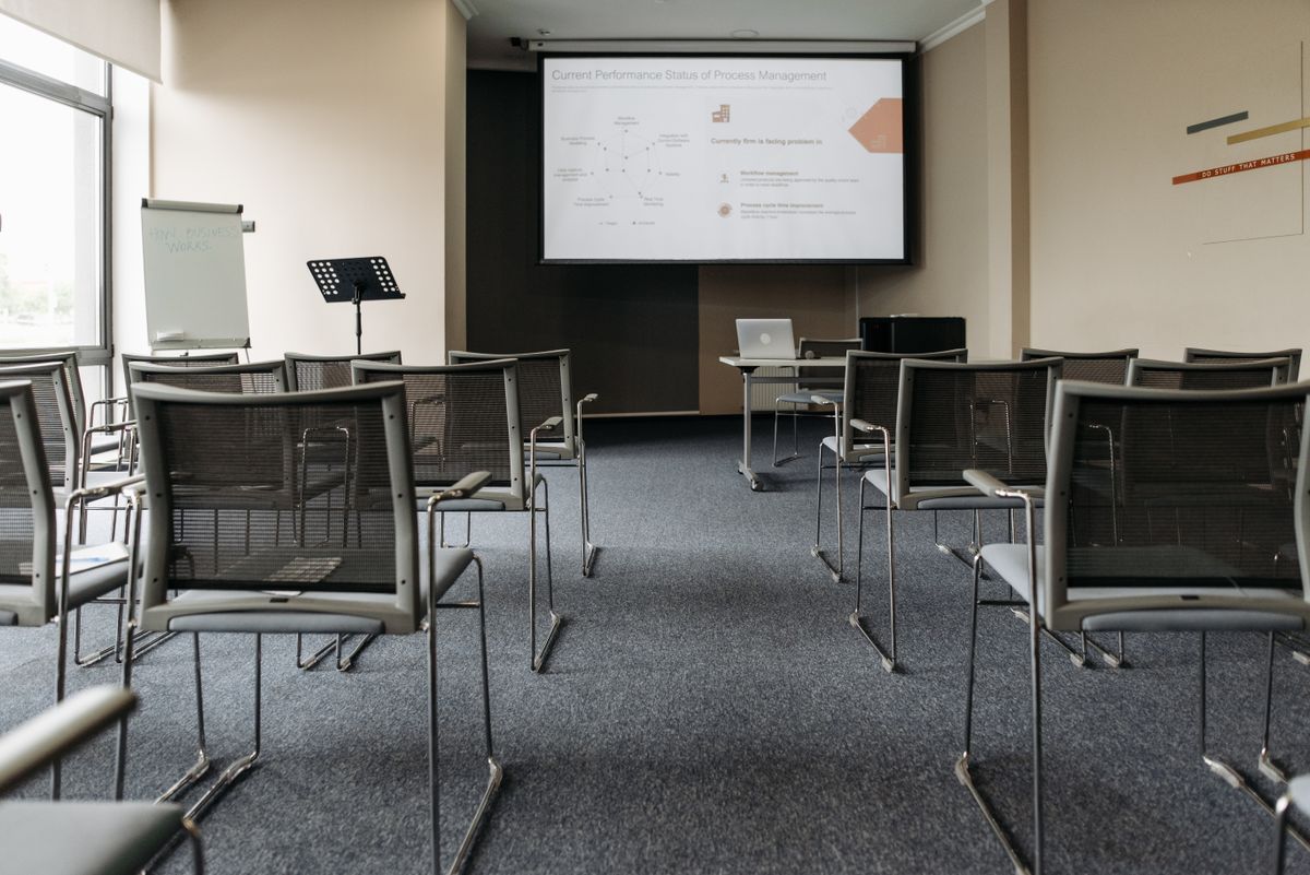 An empty conference room with rows of chairs, a projector screen, and a flip chart, representing the room layout a photographer needs to know in advance