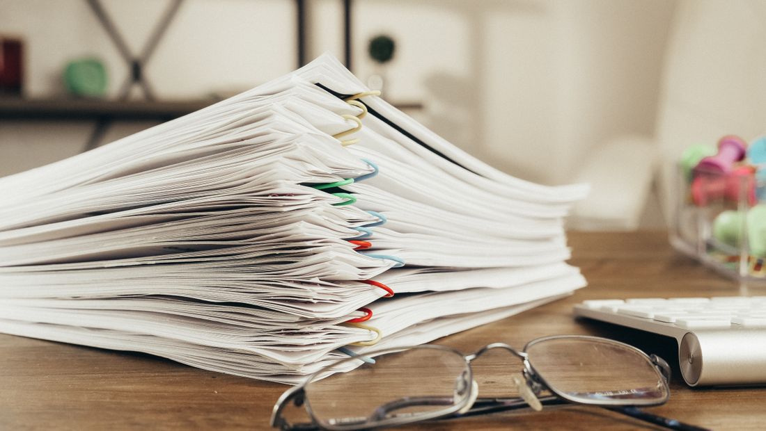 A tidy stack of paper documents held together with colorful clips on a desk, symbolizing bundled paperwork.