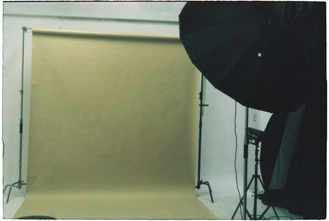 An empty photography studio set up with a seamless backdrop and studio lighting, ready for a headshot session.