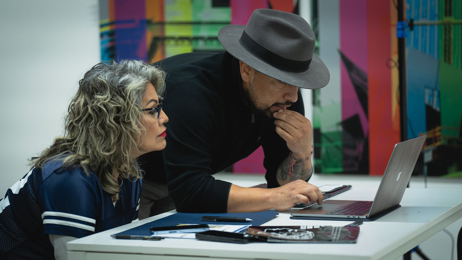 Man and woman leaning over laptop together, focused on collaborative work.