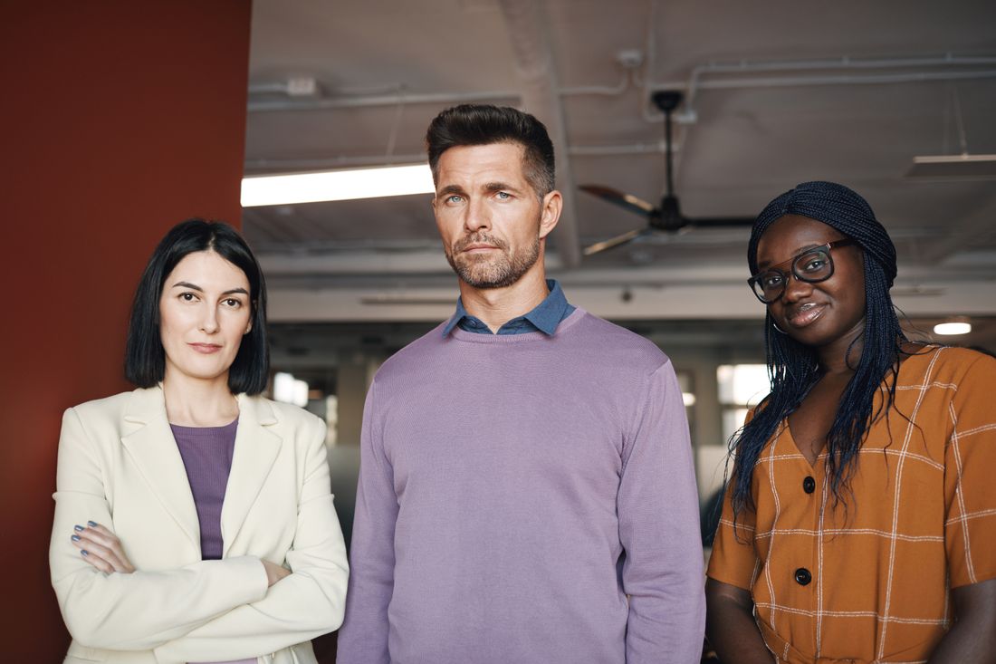 Three professionals standing together in a bright modern office.