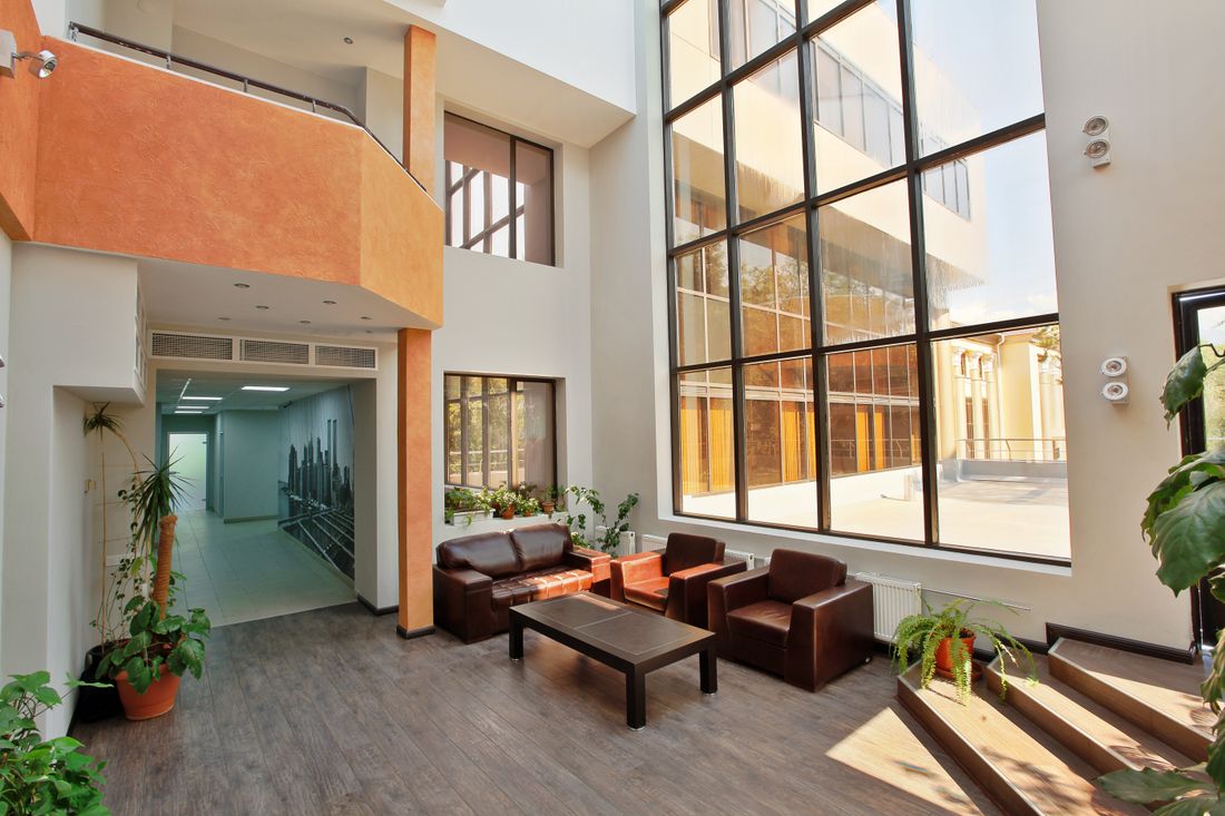 A spacious modern lobby with tall windows, open floor area, and contemporary seating.