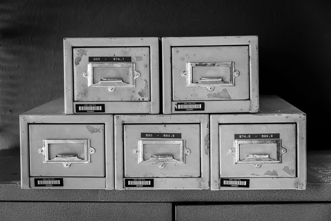 A stack of worn metal filing drawers with handwritten labels, the kind of physical record-keeping an anniversary project has to search through.
