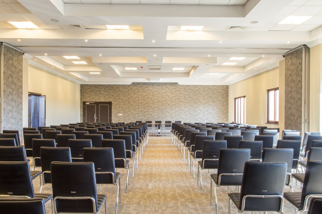Rows of empty chairs face a blank presentation screen in one breakout room before a session starts.