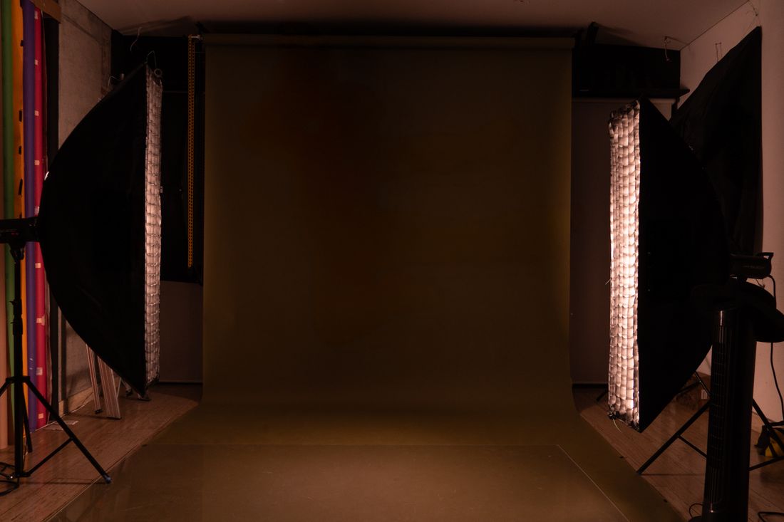 An empty portrait studio setup with a soft backdrop and softbox lighting stands ready for a shoot.