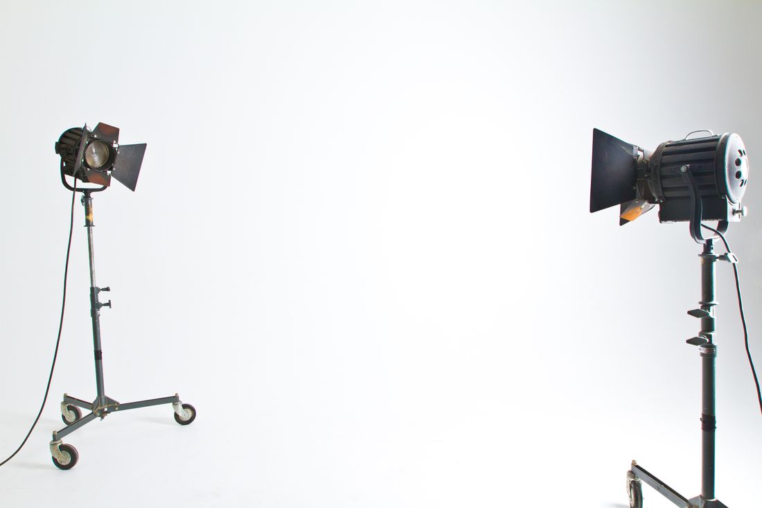 Two portable studio lights on wheeled stands set up against a clean, empty white backdrop.