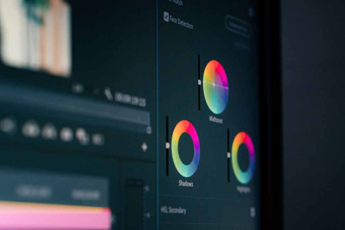 Close-up of color grading wheels on an editing monitor, adjusting shadows, midtones, and highlights.