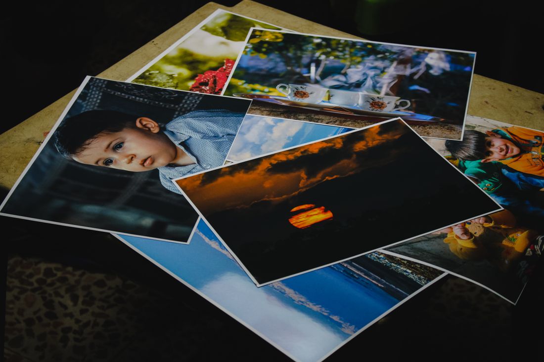 A small stack of printed photographs fanned out on a table, several images ready for review.