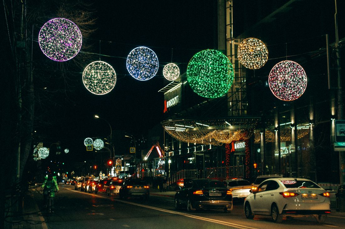 City street decorated with festive lights and glowing light spheres at night