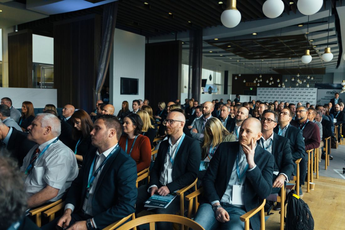 Rows of seated attendees listening in a bright room during a workplace event