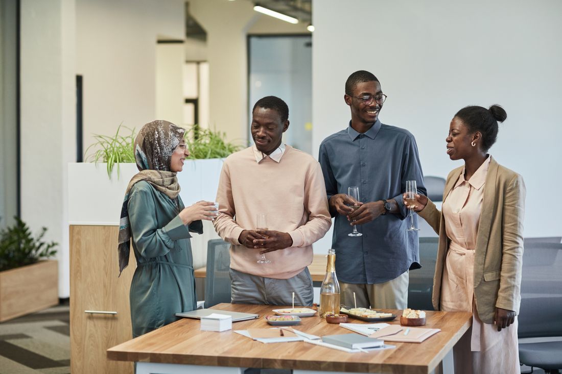 A small group of colleagues standing and talking around a table in an office common area