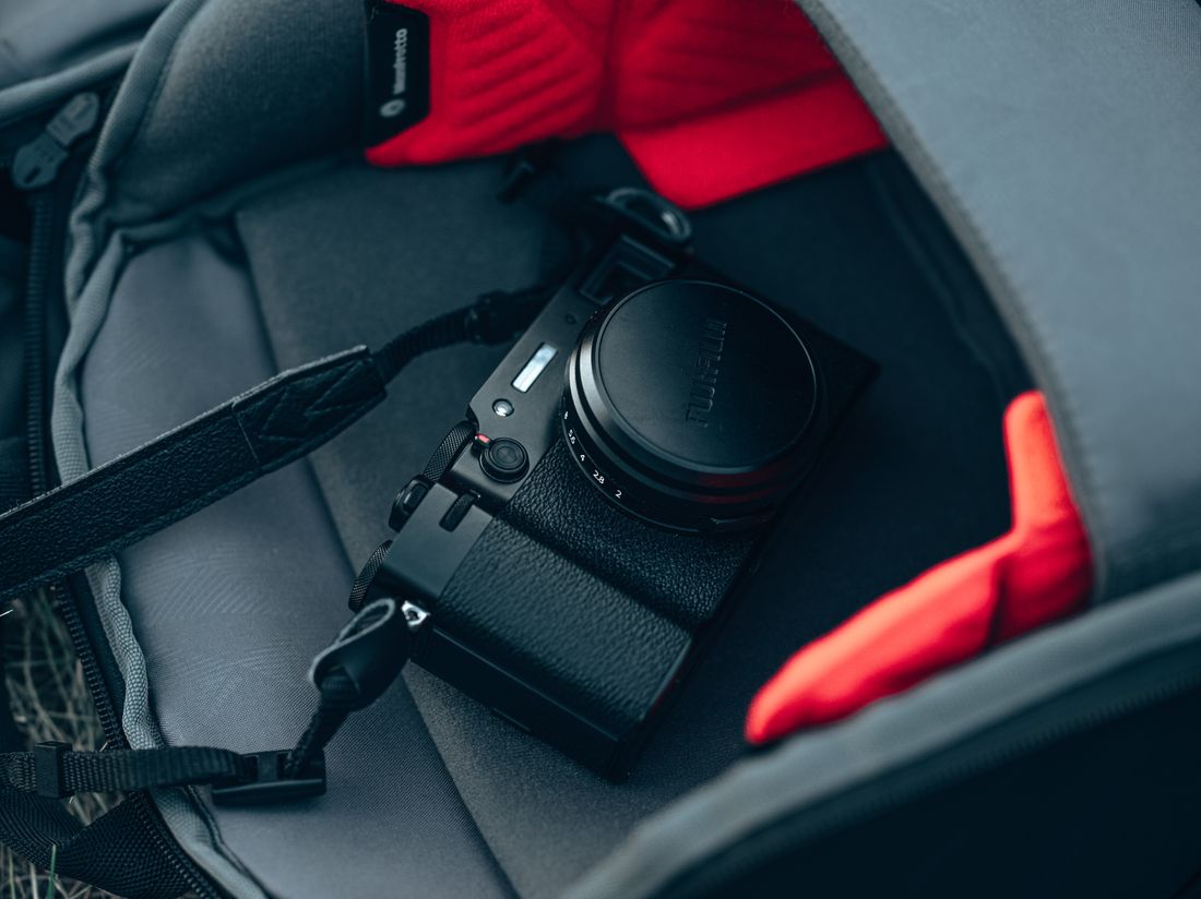 A black mirrorless camera resting inside an open camera bag, packed and ready to go.