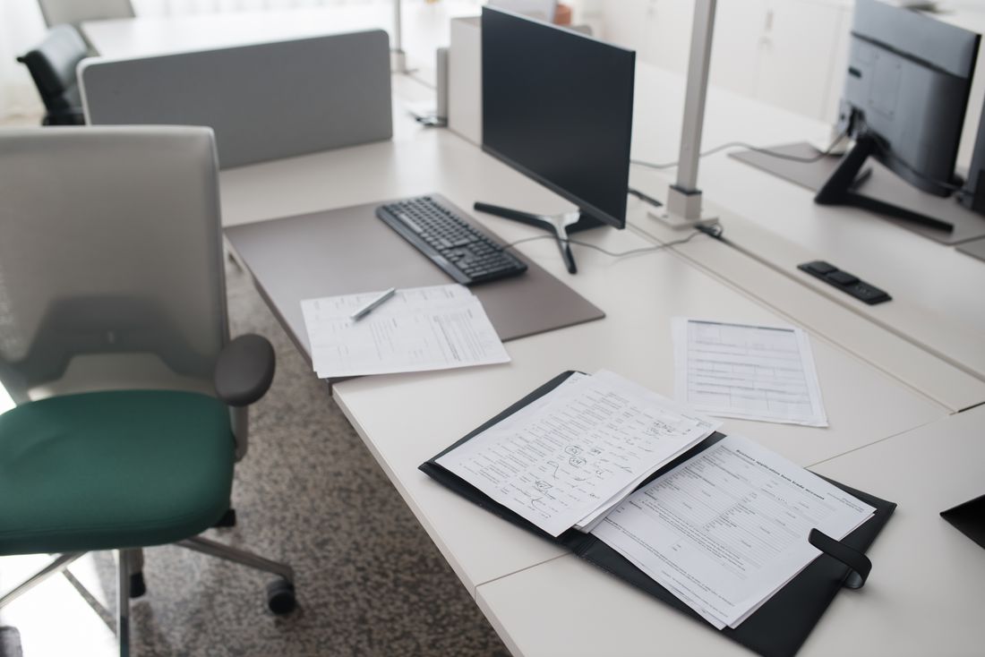 A clean, organized desk with binders and documents arranged in a modern office workspace.