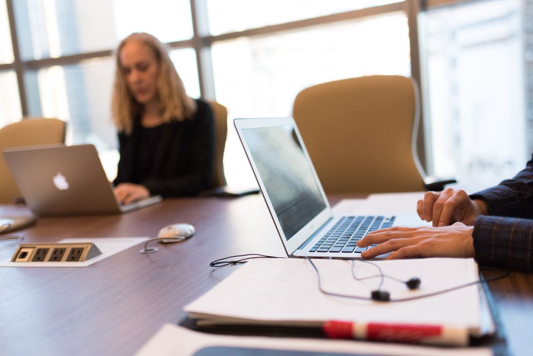 Colleagues collaborating around a laptop in a bright, modern office setting.