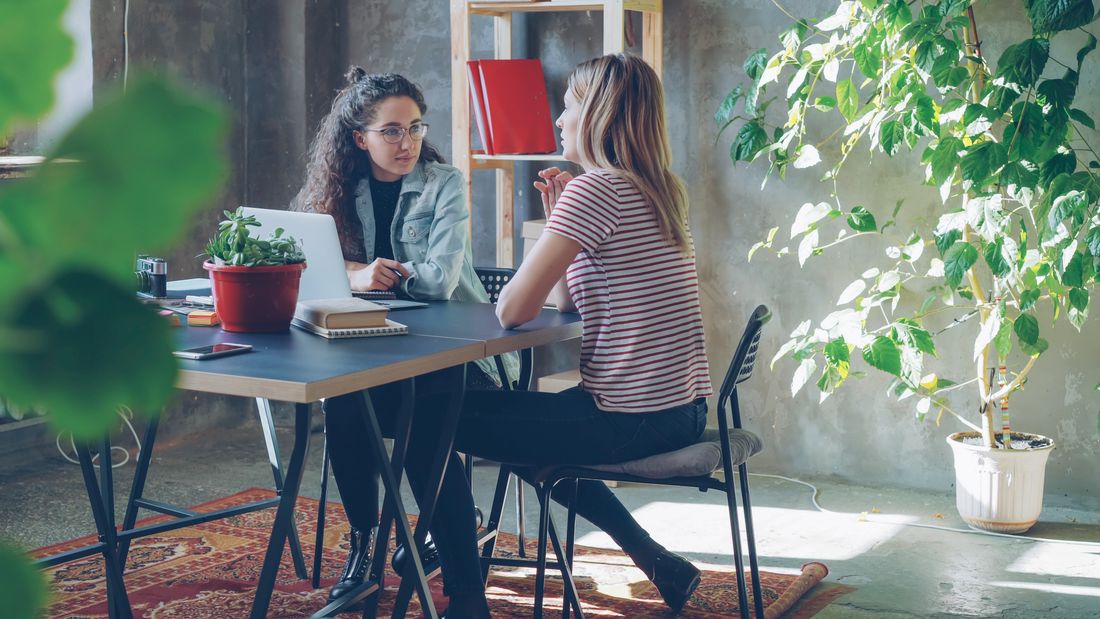 Two colleagues talking in a bright, modern office with plants, representing a small founding team's workspace