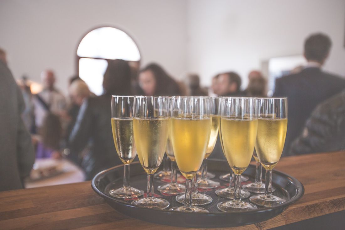 Tray of champagne flutes on a black tray with blurred gala guests mingling in the background