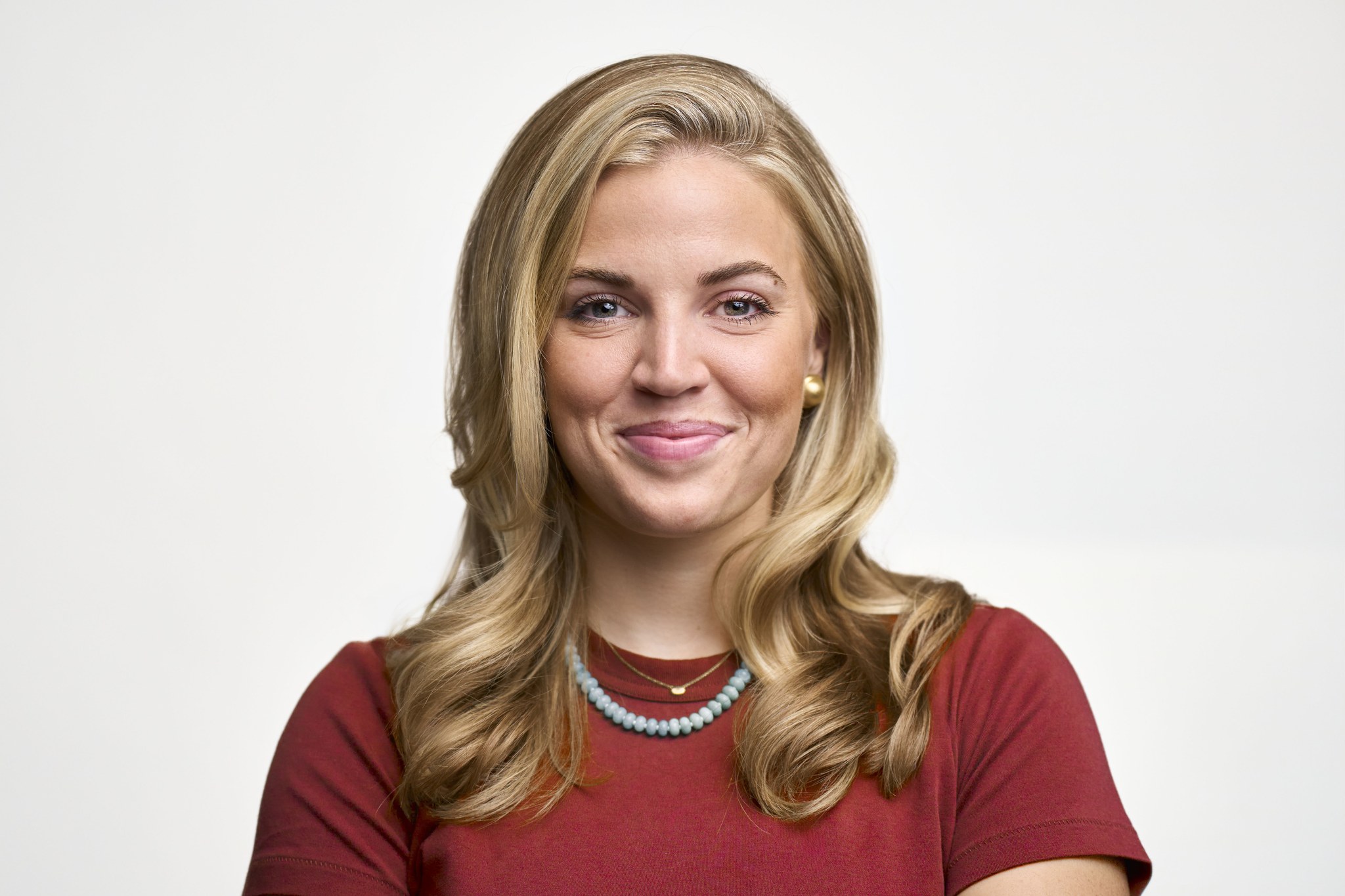 Woman with blonde hair in red t-shirt against white background.