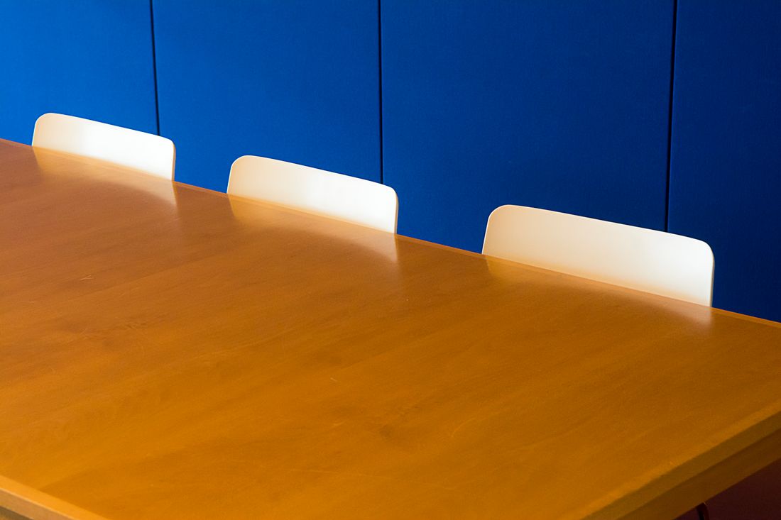 A clean, modern meeting room with a wooden table against a blue accent wall, no one present.