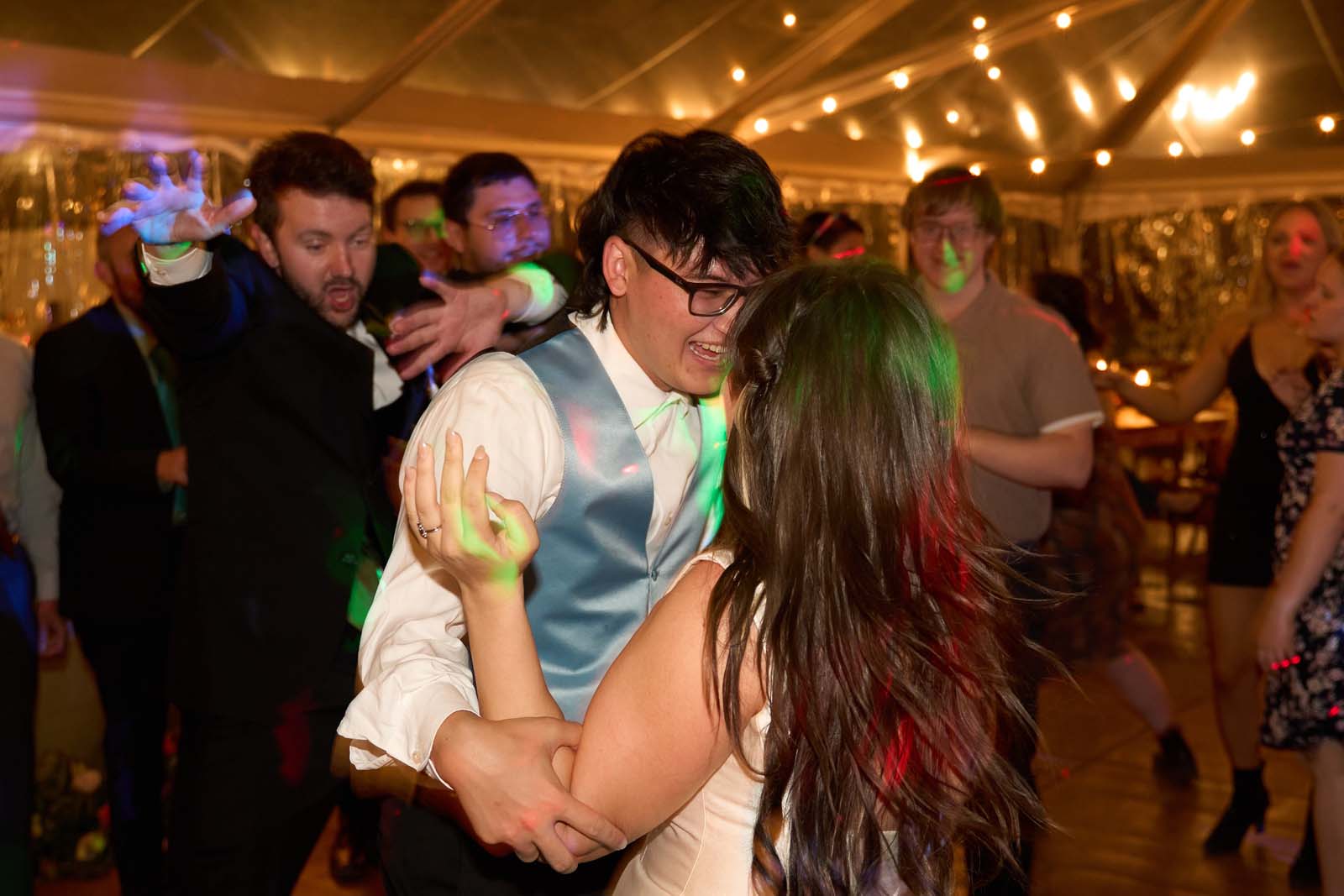 Couple dancing closely under green and red stage lights.