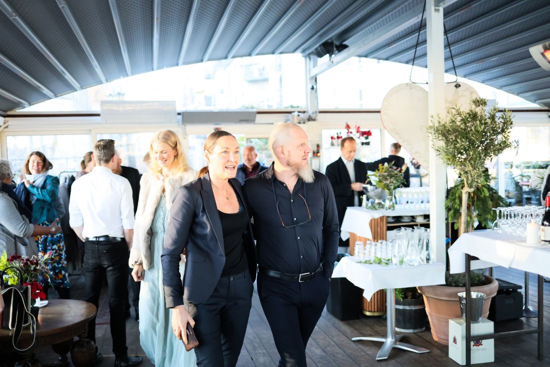 Well-dressed guests mingling and talking at an elegant evening reception under a covered venue space.