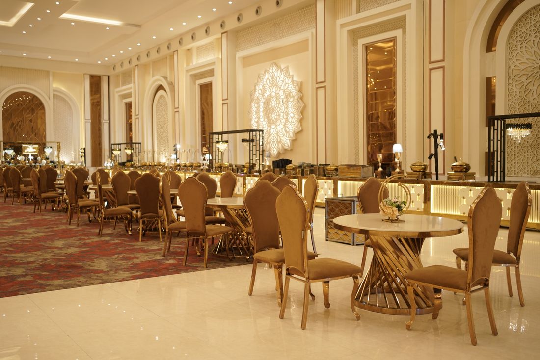 An empty, elegantly set banquet hall with round tables and chairs, quiet before guests arrive for an evening event.