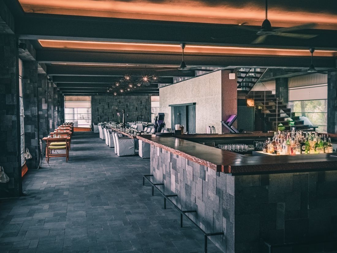The dark-toned bar and dining room of a modern restaurant, shown as architecture rather than a food scene.