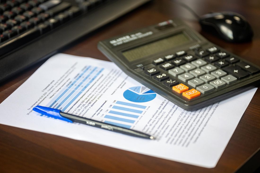 Desk with calculator, financial report, and pen for cost analysis