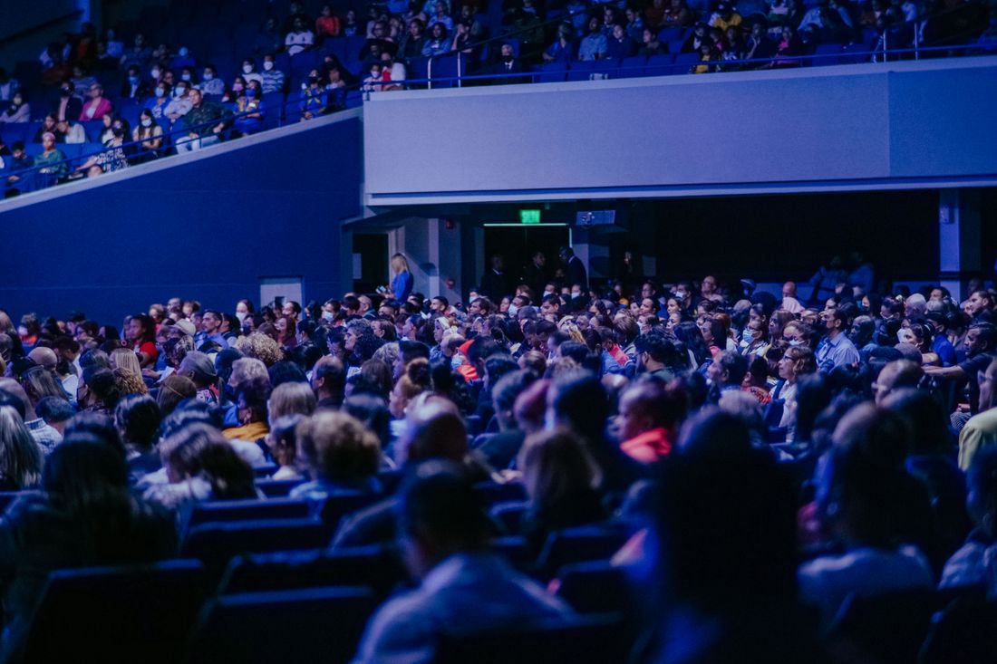 A packed conference hall with rows of attendees listening to a speaker, illustrating how room size and crowd density affect event photo coverage