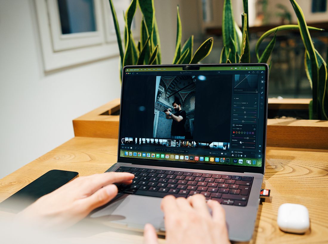 A photographer reviewing and editing event photos on a laptop in a modern office setting