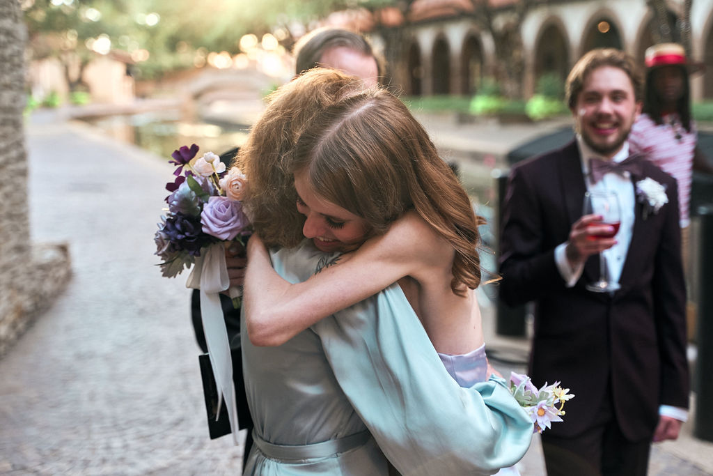 Two women hugging outdoors at wedding reception venue.