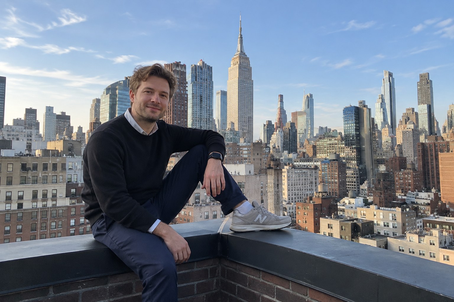 Professional on rooftop overlooking Empire State Building and Manhattan skyline.