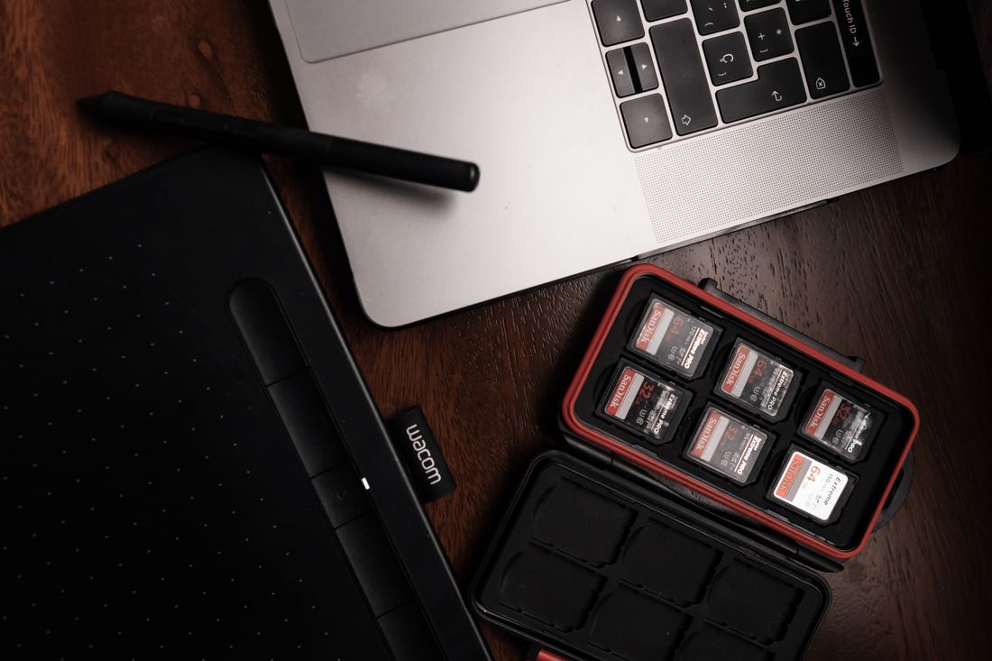 Memory cards next to a laptop on a desk, representing digital file storage and archiving.