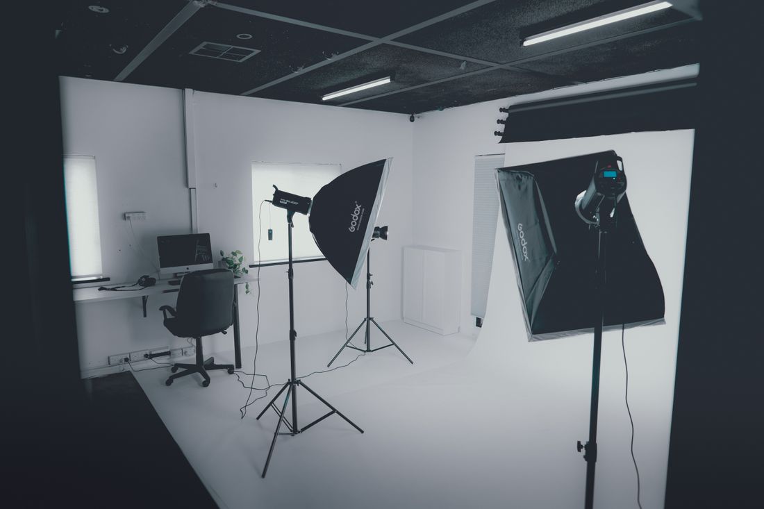 Empty photography studio with softbox lighting and a computer workstation, set up for a headshot session