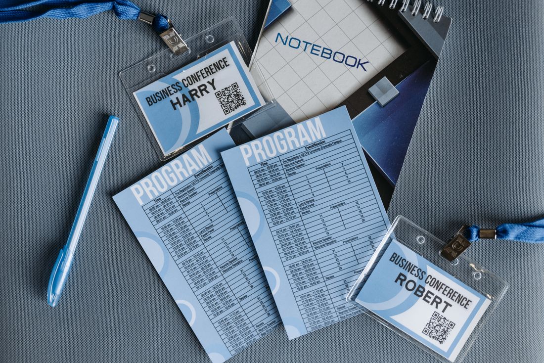 Flat lay of conference badges, program materials, and notebook on a table