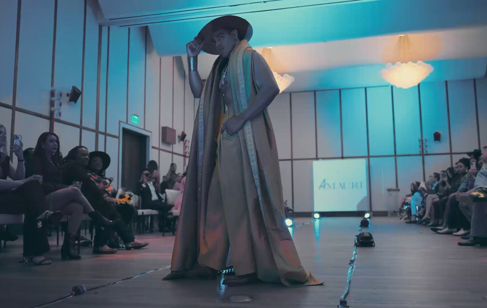 A performer on stage in front of a seated audience at a professional event or concert.
