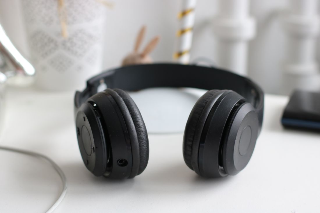 A pair of black over-ear headphones resting on a desk.