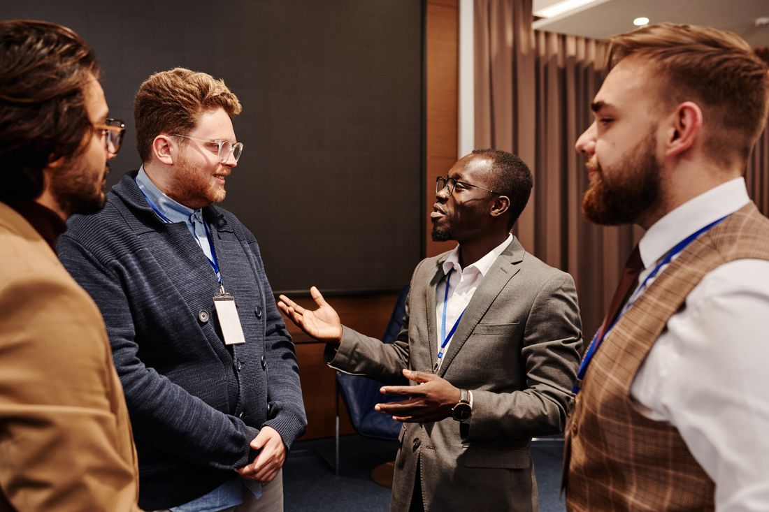 A small group of professionals stands close together in animated conversation during an indoor networking event.