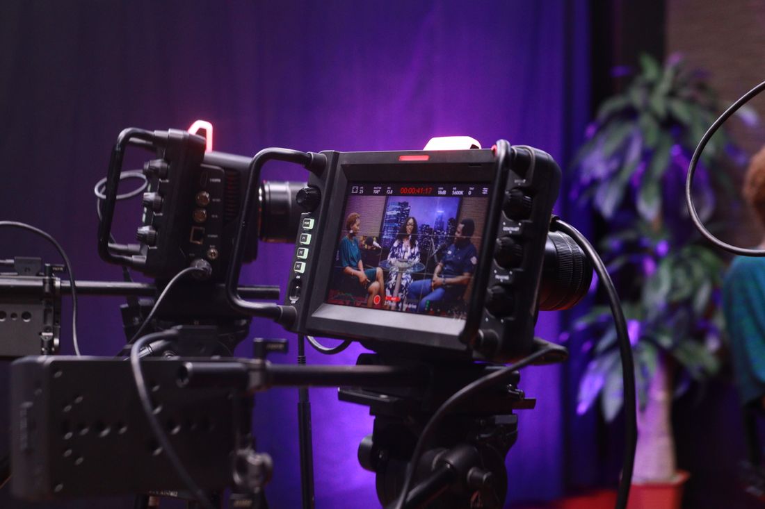 A camera monitor displaying a video interview scene during a studio recording session.
