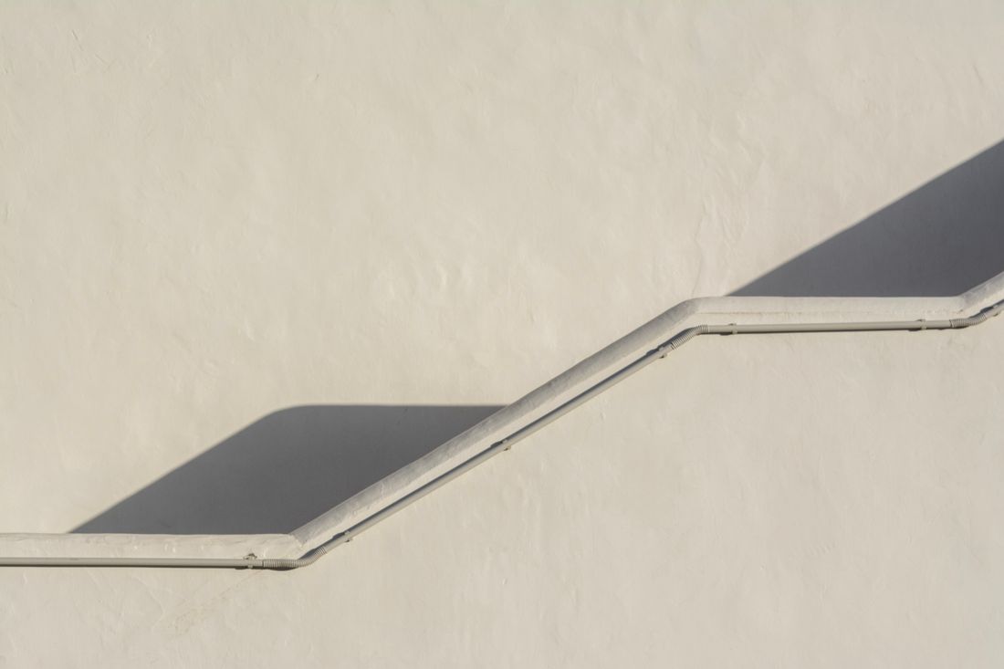 Soft diagonal shadow falling across a plain pale wall, leaving open empty space