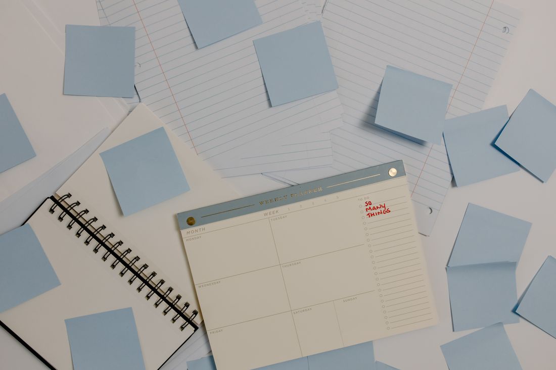 Overhead view of a day planner surrounded by blank sticky notes, mapping out a content calendar