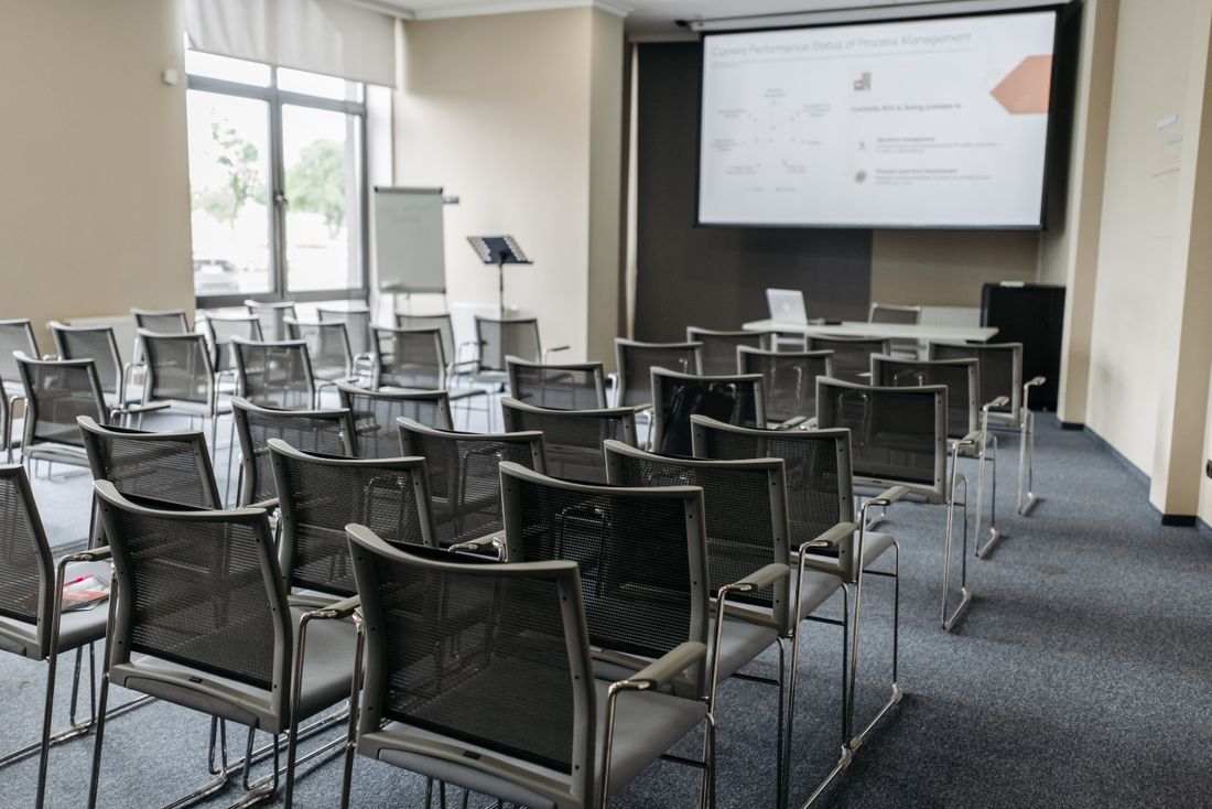 Empty conference room set classroom-style with rows of chairs facing a presentation screen, ready for a business meeting