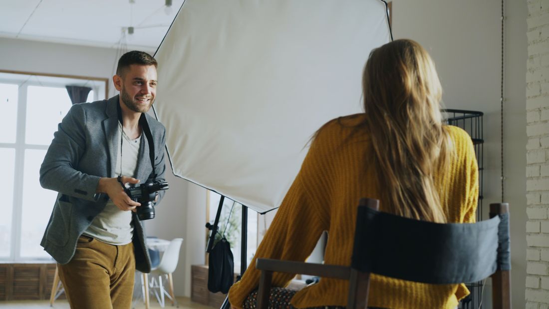 Photographer adjusting studio lighting while photographing a subject during an indoor portrait session
