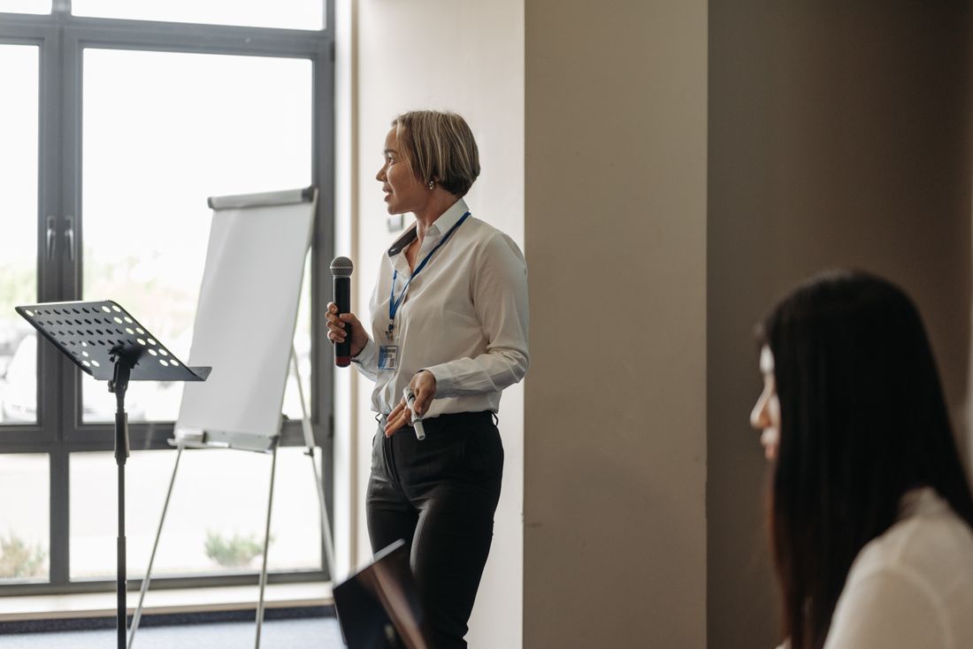 Coach speaking with a microphone beside a flip chart during a small workshop session