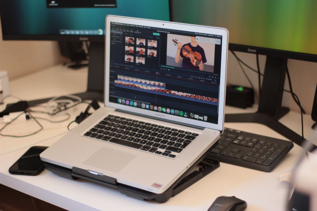 Laptop screen showing video editing software timeline on a desk