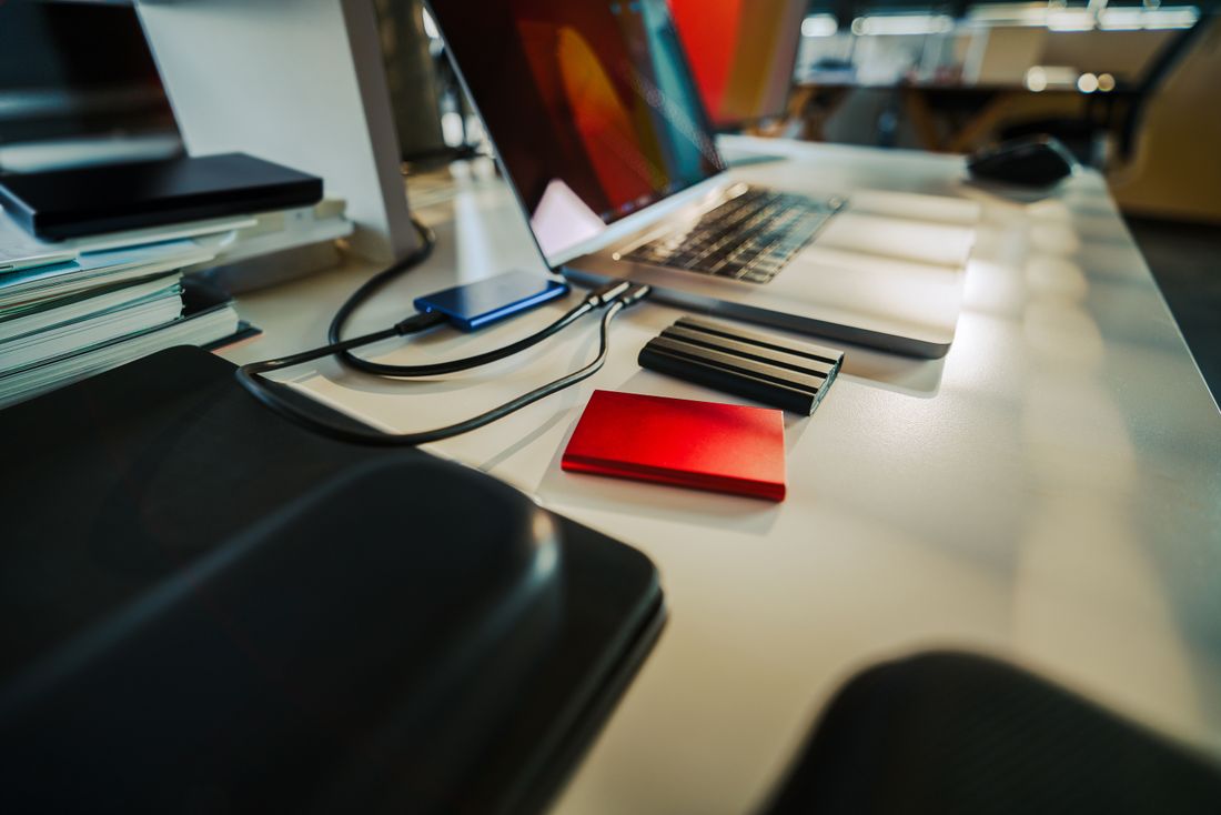 Desk workspace with a laptop and external storage drives where finished photo files are kept and organized