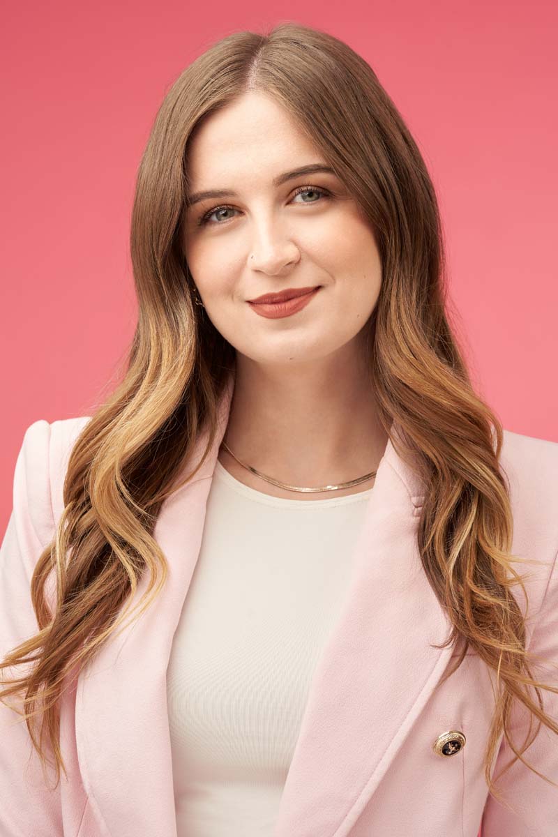 Smiling woman in pink blazer poses for professional headshot.