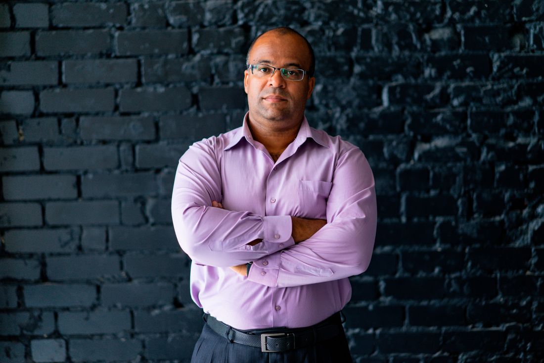 Portrait of a man in a collared shirt against a plain dark wall, in the register used for faculty and staff headshots