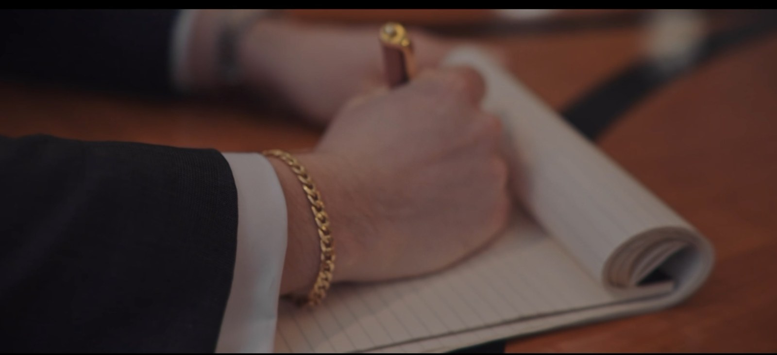 Two hands clasped together with gold chain bracelet, symbolizing partnership.