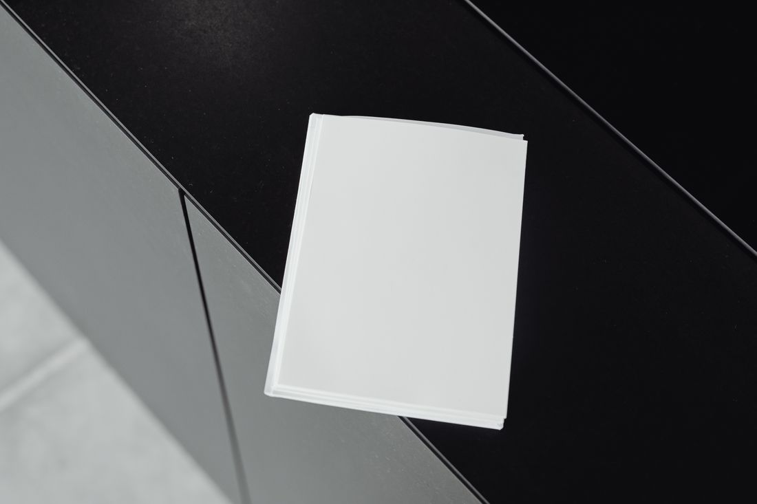 A blank stack of white printed sheets resting on a plain dark surface.